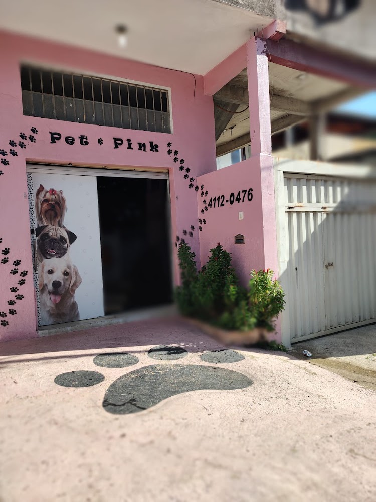 Fachada rosa do Pet Pink com o nome pintado na parede, pegadas de patinha decorativas e adesivos de cachorros na porta de entrada